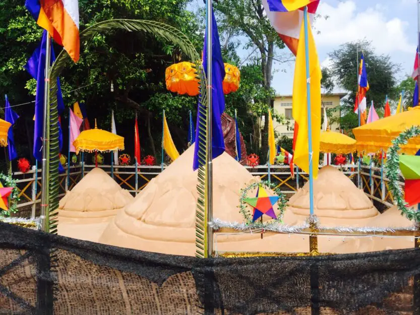 Sand mountain covered in red, yellow and blue flags and bunting at Wat Bo Pagoda for Khmer New Year in Siem Reap 2024