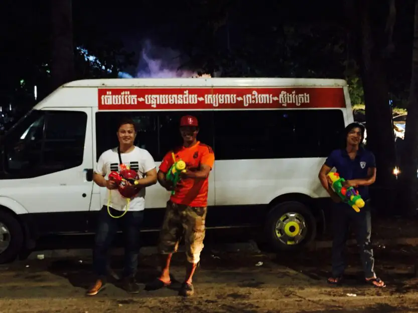 Three locals standing in front of a white van with water guns during Khmer New Year water fights in Siem Reap
