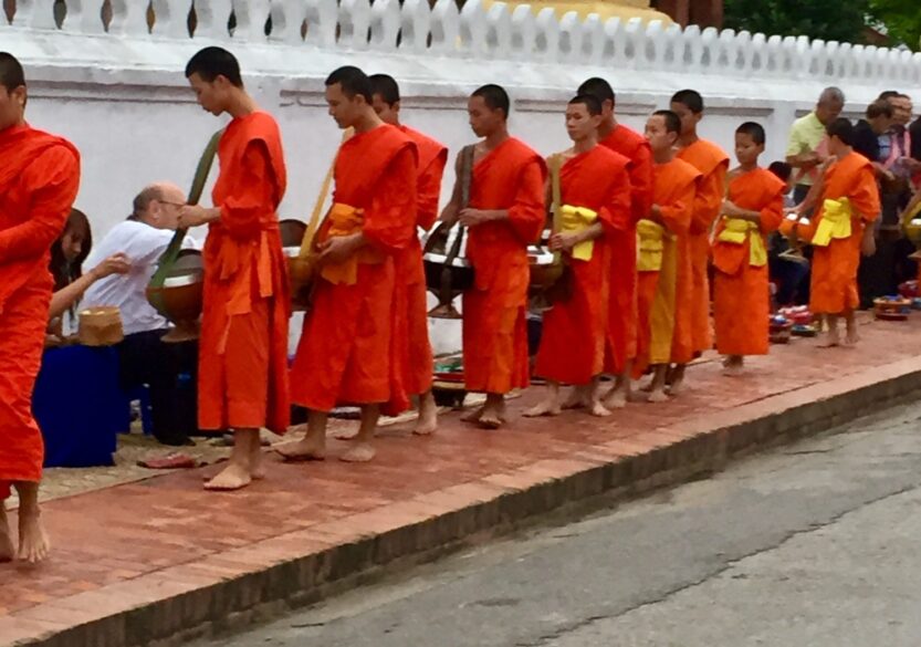 Monks in orange robes at Tak Bat alms giving in Luang Prabang