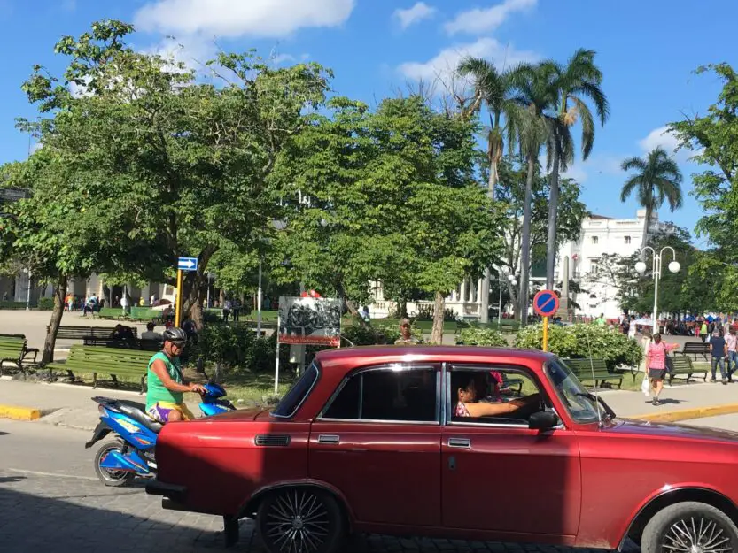 Santa Clara Cuba, plaza with old red car in the foreground.