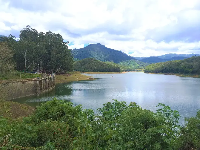 A beautiful lake, mountain, trees and an old dam to the left of the picture.