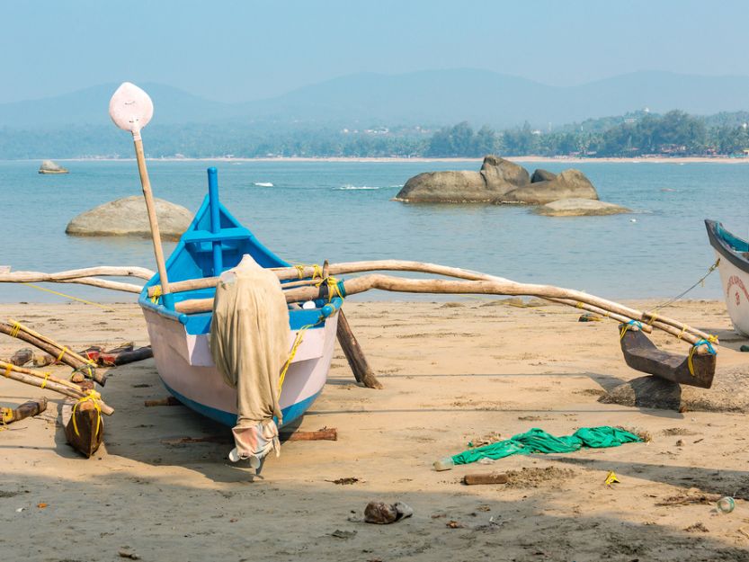 Blue and white rwoinf boat on the shore of Agonda Beach in South Goa