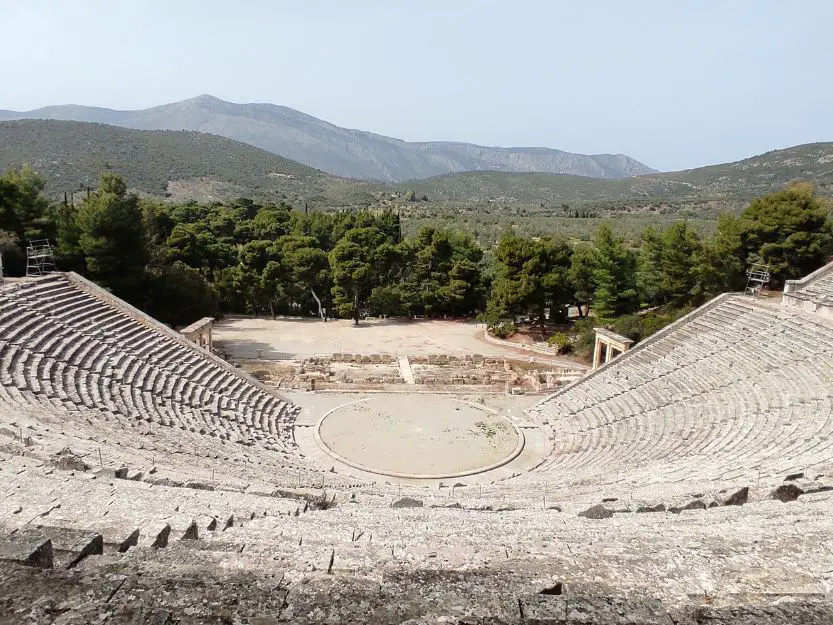 Epidaurus Amphitheatre with green trees and mountains in the background.