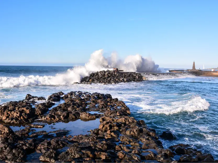 Bajamar Village. Image of natural swimming pool with rocks in the foreground and crashing waves and blue sky in the background