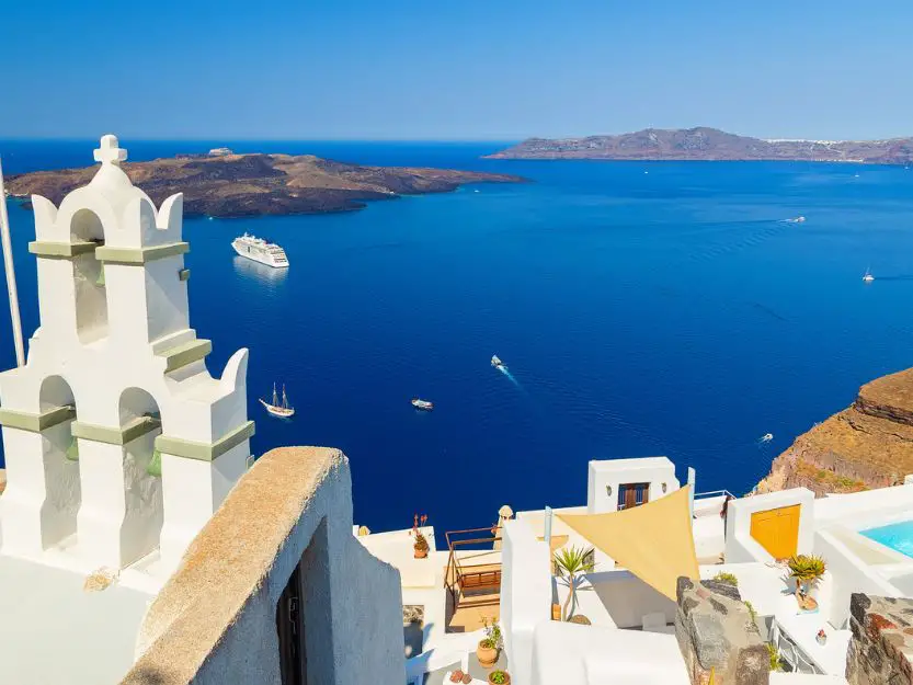 White bell tower of Orthodox church with view over volcanic caldera at Fira, Santorini 