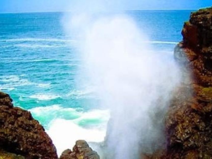 Blow Hole Hummanaya with water spraying up in between the holes walls with blue sea and sky in the background.