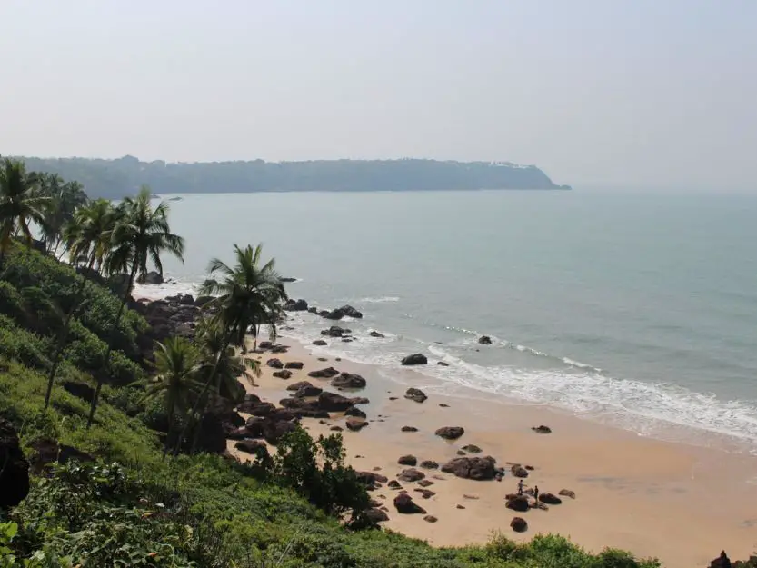 Cabo de Rama Beach in South Goa. Palm trees and rocks on beach.