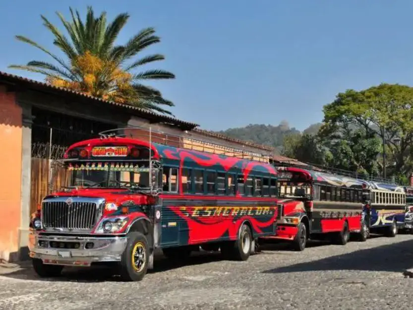 Red, black and yellow chicken buses in Antigua, Guatemala