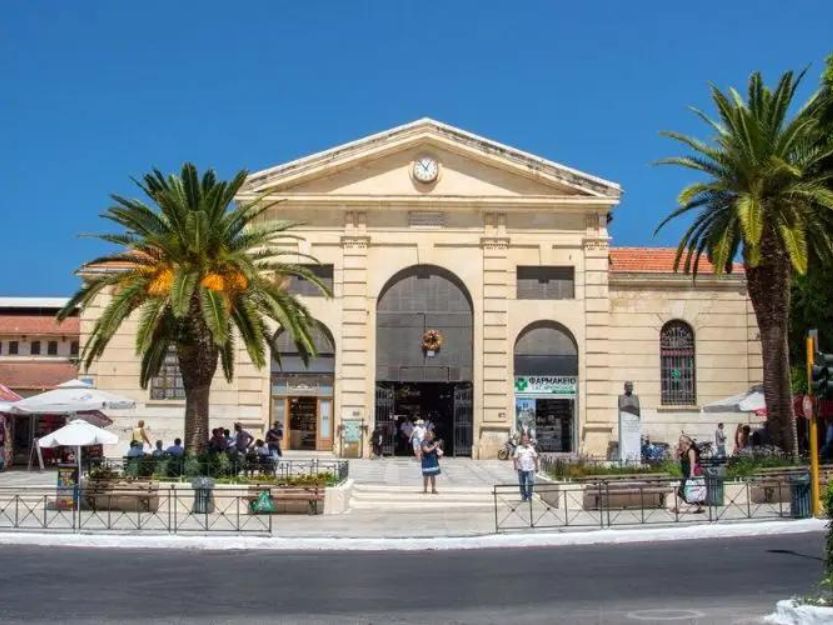 Agora Central Market in Chania, a sandstone coloured building with a palm tree each side.