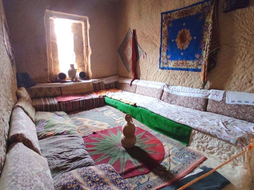 Inside of historical cave house in Cavusin village full of colourful rugs and cushions