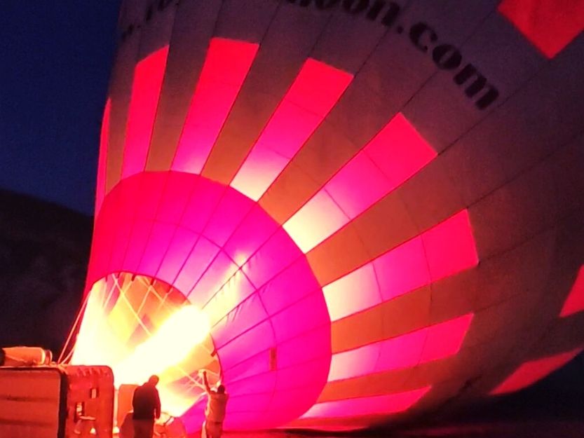 Royal Balloons Cappadocia Red and Black Hot Air Balloon, with the gas burner lit up in the dark