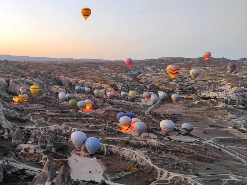 Hot air balloons taking off at dawn over Cappadocia