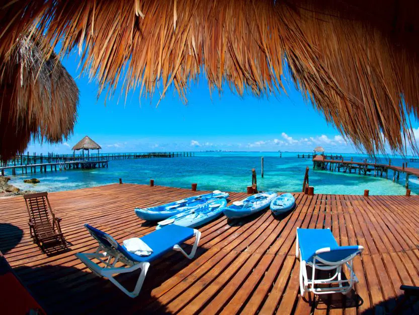 Isla Mujeres by ferry in Mexico - image of blue sunbeds on a brown wooden deck with blue sea in the background