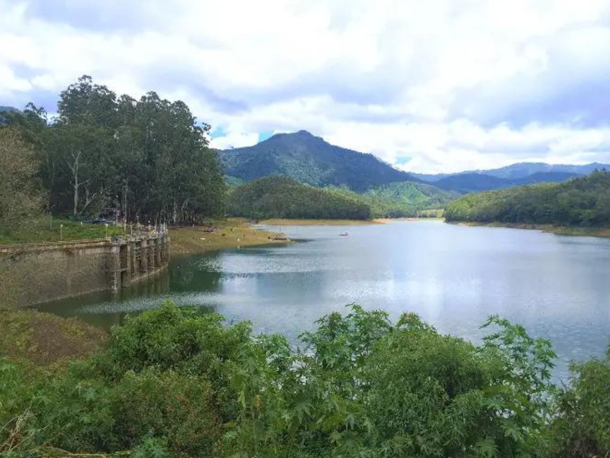 A beautiful lake, mountain, trees and an old dam to the left of the picture.