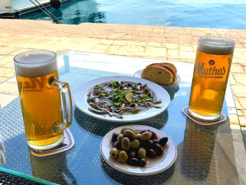 Greek beer and meze on the table outside Millenium Cafe Bar in Erminoi. Blue sea in the background.