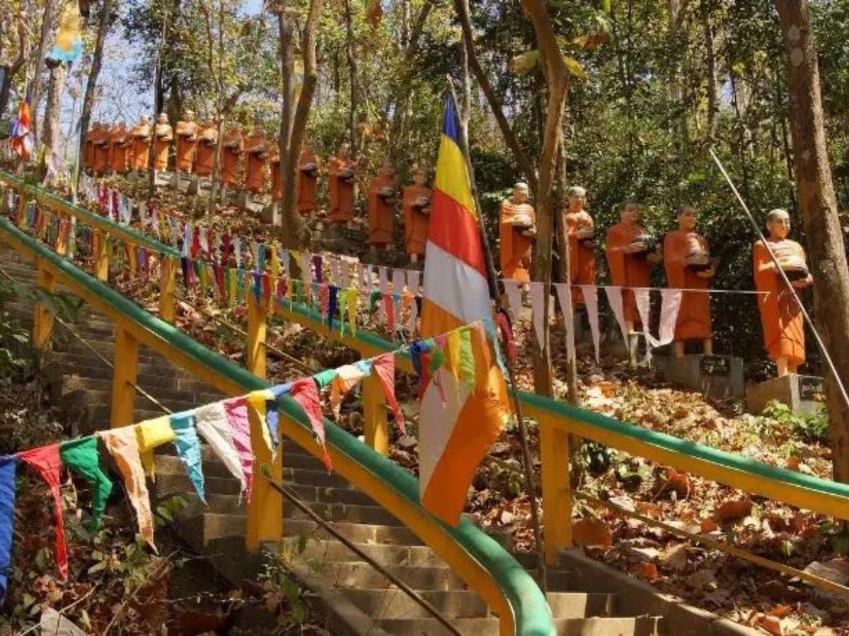 Off the Beaten Track in Cambodia, Asia. Steps up to a temple with statues and colourful flags amongst trees