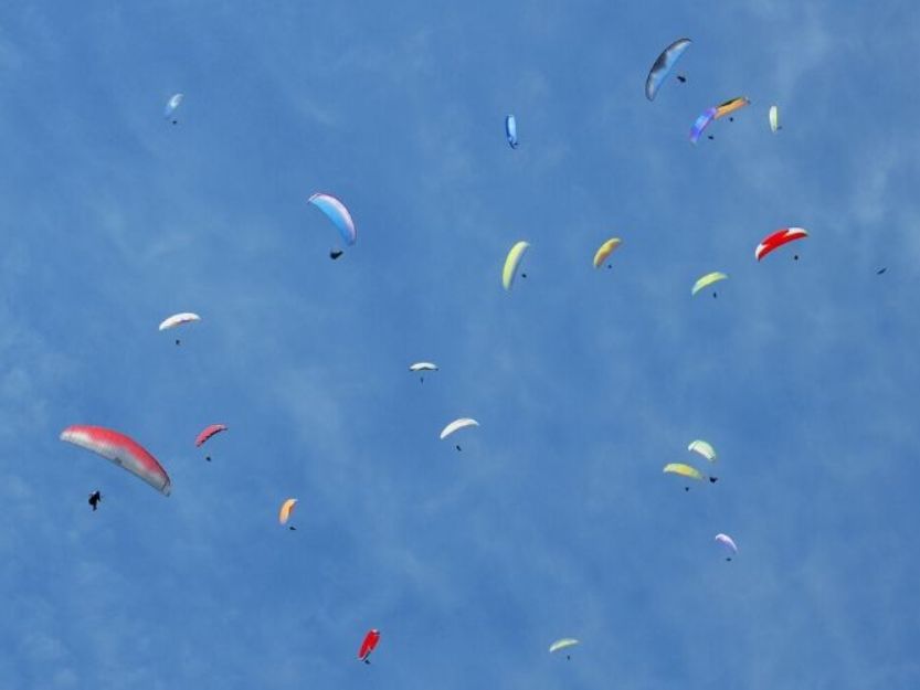 Paragliding in Pokhara, Nepal. Many colourful paragliders against a blue sky