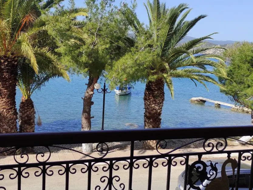 Balcony view at Philoxenia Ganossis in Ermioni. Overlooking the blue sea with palm trees in front.