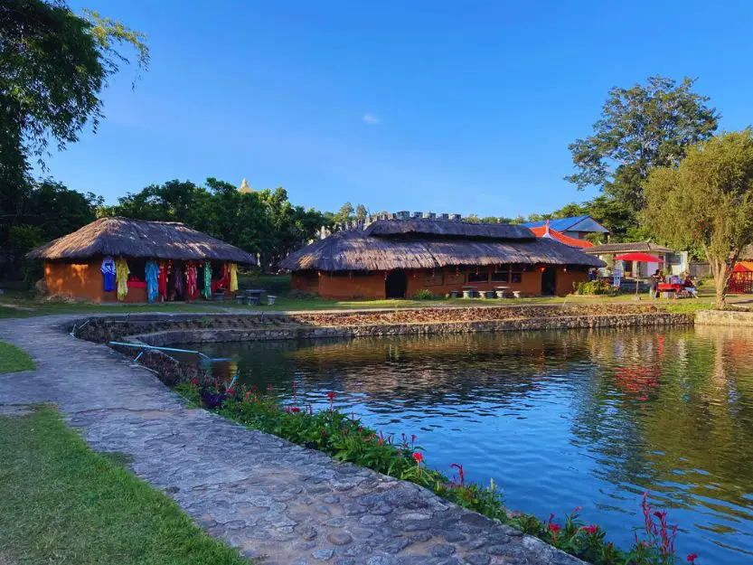 Santichon Village (Chinese Village) in Pai, Thailand. Traditional clay houses on the waters edge with a paved path around edged with green grass.