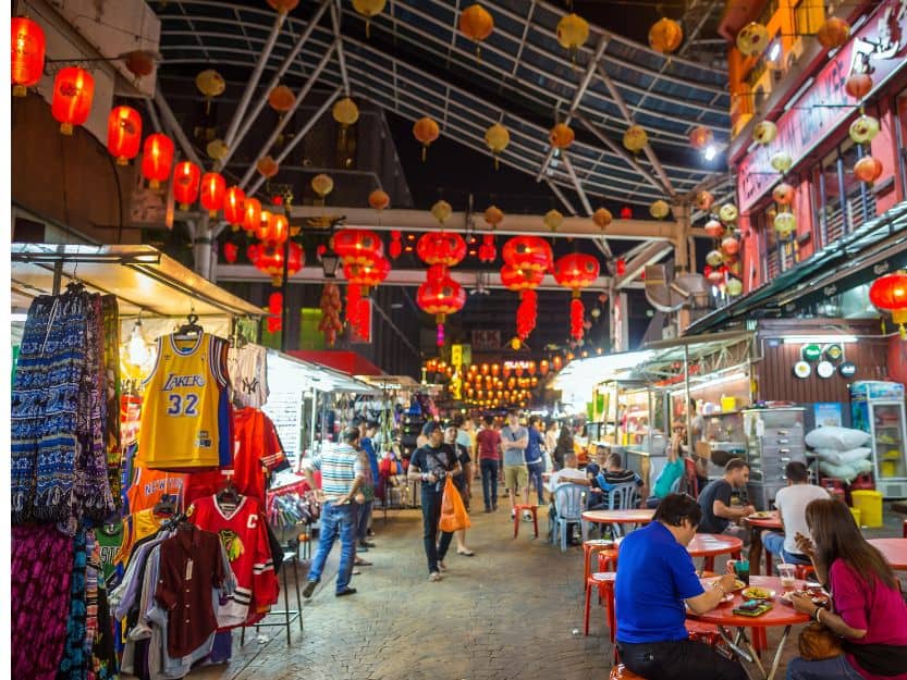 Street in Chinatown in Kuala Lumpur Street in Chinatown, in Kuala Lumpur, Malaysia with clothes stalls, people eating and red lanterns.