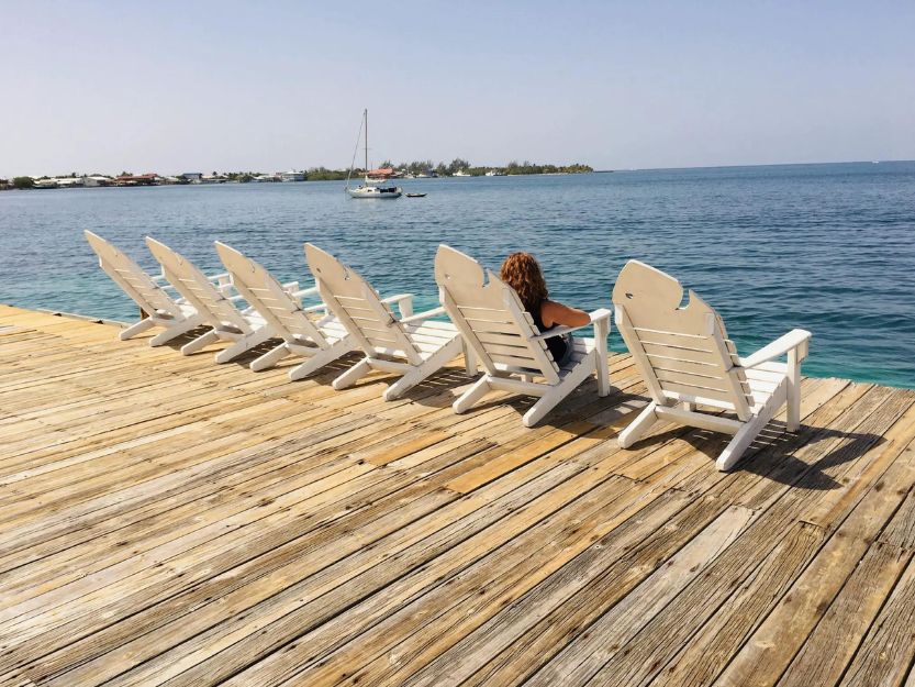 Tanya sitting on a white sunchair, looking out to sea on the sundeck at Utila Lodge on Utila in Honduras