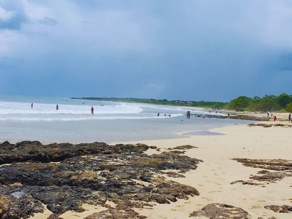 Things to Do in Playa Avellanas in Costa Rica - yellow sand beach with rocks in the left foreground and sea and sky in the background