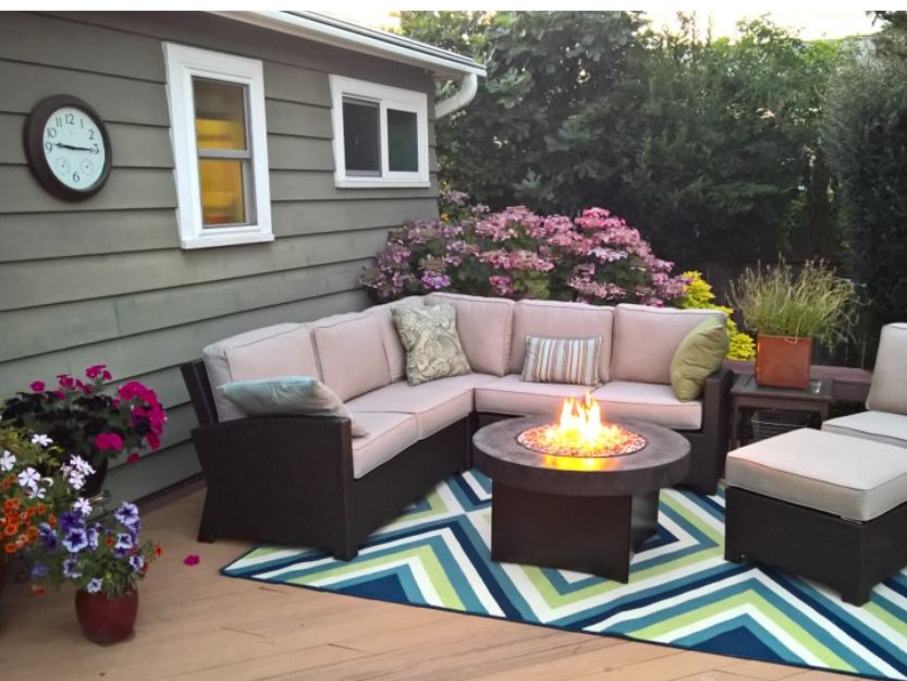 Work from anywhere with Noad Exchange,cosy outdoor sofa around a firre pit with a colourful zig zag blue and green patterned rug underneath.